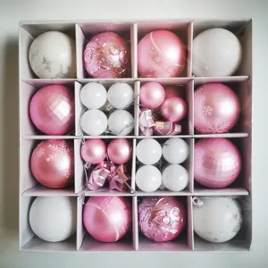 Overhead view of various pink and white Christmas ornament balls set in a grid gift box.