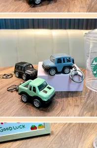 Detailed view of mini alloy off-road car keychains in three colors on a wooden surface.