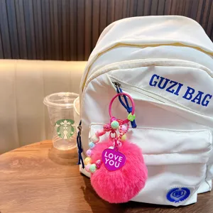Cute pink pom pom keychain with colorful beads and heart charm shown on white backpack