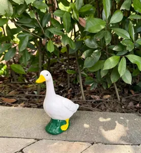 Vista detallada de una estatuilla de ganso blanco colocada en un entorno de jardín natural