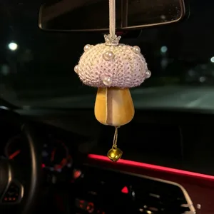 Close-up detail of a sea urchin shell mushroom charm hanging inside a car interior