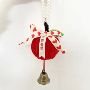 Detailed view of handmade corduroy apple ornament with brass bell and pearl string