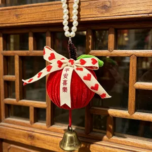 Detail view of a handmade red plush Christmas apple ornament with a golden bell and heart ribbon.