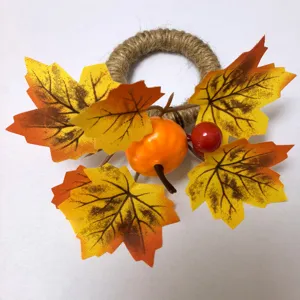 Close-up of autumn napkin ring with artificial pumpkin and yellow maple leaves