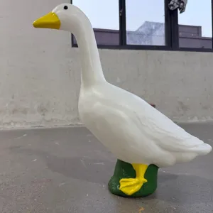 Side view of a 22-inch white goose garden sculpture standing on a green grass base