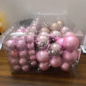 Detailed view of pink and gold Christmas ball ornaments set in a clear transparent gift box