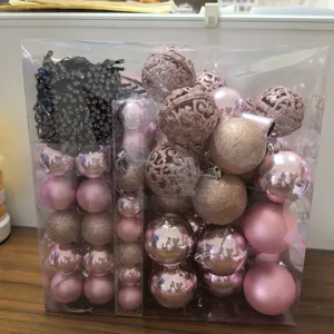 Detailed view of the pink Christmas ornament set and LED light string in a clear gift box.