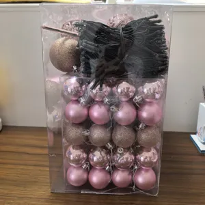 Set of rose gold Christmas ornaments and LED string lights in a clear packaging box