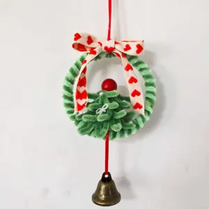 Detail van handgemaakte groene pijpenrager kerstkrans met hartjesstrik en bronzen belletje