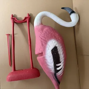 Pink plastic flamingo garden ornament with red decorative stand for outdoor lawn decor.