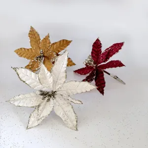 Close-up detail of three artificial glitter poinsettia flowers in white, gold, and burgundy.