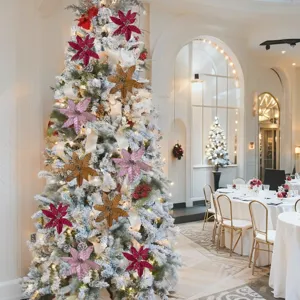Glittery artificial poinsettia flowers decorating a snow-flocked Christmas tree in a room