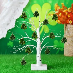 Green shamrock ornaments hanging on a white decorative tree for St. Patrick's Day decor.