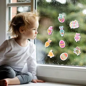 Niño mirando pegatinas de Pascua con conejitos y huevos en un cristal bajo la lluvia