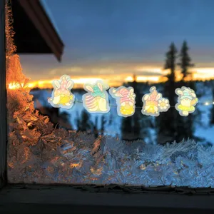 Pegatinas de gnomos de Pascua con luces LED en una ventana helada al atardecer