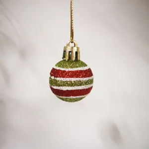 Close-up of a 3cm mini Christmas ball with glittery red, green, and white stripes