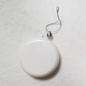Close-up macro view of a plain white flat circular Christmas ornament with silver hanging string