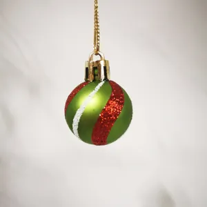 Close-up of a 3cm green mini Christmas ball with red and white glitter stripes