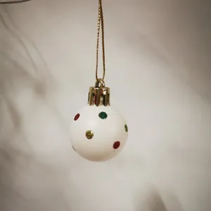 Close-up of a 3cm white mini Christmas ball with festive glitter dots for tree decor