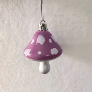 Detail showing a purple mushroom ornament with white spots and silver hanging string.