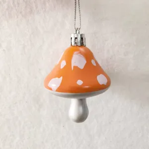 Close-up view of orange painted mushroom ornament with white spots and silver chain