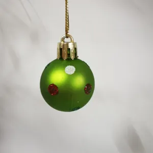 Close-up detail of a 3cm green mini Christmas ball with red and white dots