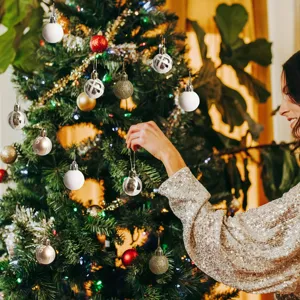Close-up of hand decorating Christmas tree with 3cm mini assorted ornaments set
