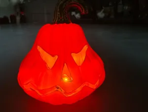 Close-up of a glowing red plastic Halloween Jack-o'-lantern pumpkin lamp decoration