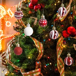Close-up of assorted patterned mini ornaments hanging on a glowing Christmas tree branch.