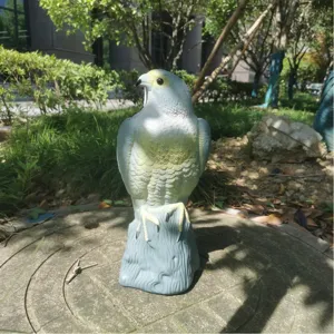 Vue détaillée d'une sculpture de faucon leurre réaliste anti-oiseaux dans un jardin