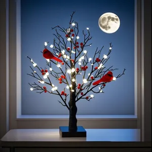 Árbol artificial iluminado con pájaros rojos y bayas frente a una ventana nocturna con luna llena