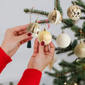 Close-up of hands hanging a gold snowflake bauble from a Christmas ball set