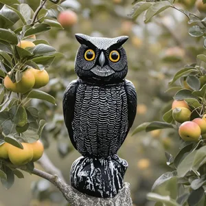 Vista detallada de un señuelo de búho realista en una rama de manzano para aves.