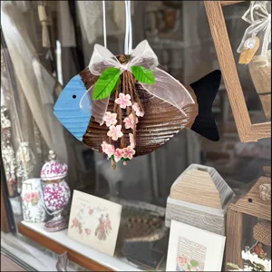 Close-up of a rustic Mediterranean hanging fish ornament with pink flowers and white bow