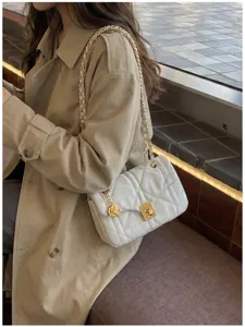 Detailed view of a white quilted square chain bag with a rose charm on a model's shoulder