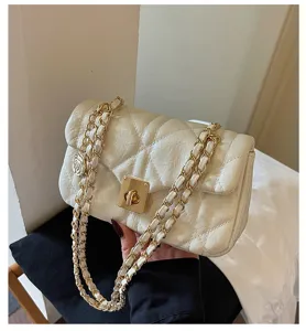 Detail shot of a cream quilted crossbody bag featuring a golden chain strap and turn-lock.