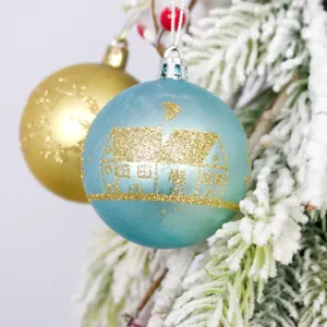 Decorative 6cm blue and gold Christmas baubles set hanging on a snowy pine tree branch