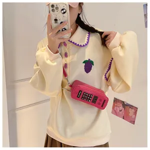 Detail shot of a creative retro brick phone-shaped pink crossbody bag worn on model