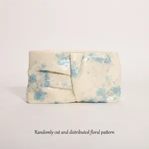 Vista dettagliata della pochette plisse con paillettes e motivo floreale vintage casuale.