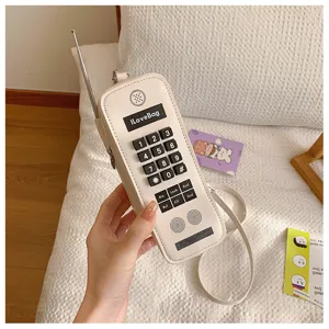Detail view of a retro mobile phone-shaped shoulder bag in cream white with buttons