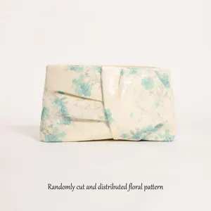 Dettaglio della pochette di paillettes con motivo floreale blu e trama plissettata.