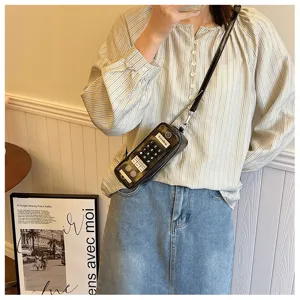 Detail view of a creative retro telephone shaped crossbody bag worn by a model
