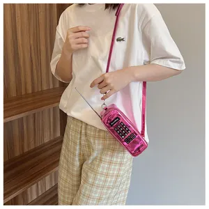 Detail shot of a creative pink vintage brick phone shaped crossbody bag worn by a model.
