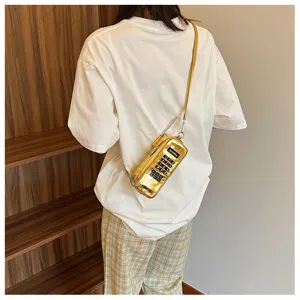 Unique golden vintage brick phone shaped crossbody bag shown on a model from behind.