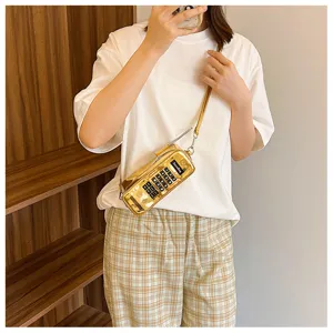 Model wearing a creative gold brick phone shaped crossbody bag with number keypad.
