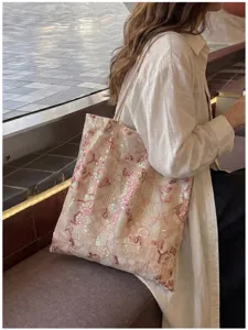 Pink sequin shoulder bag with geometric embroidery on model in a stylish outdoor setting