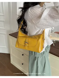 Detailed view of a vintage yellow oil-wax leather shoulder bag on a model.