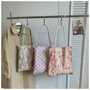 Trio of colorful sequin underarm bags with geometric embroidery displayed on a rack
