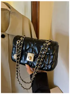 Detailed view of a black quilted oil leather handbag with a gold chain strap and lock.