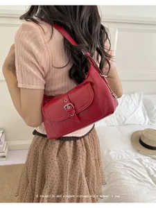 Detail view of a vintage red oil wax leather underarm bag worn by a model in a bedroom